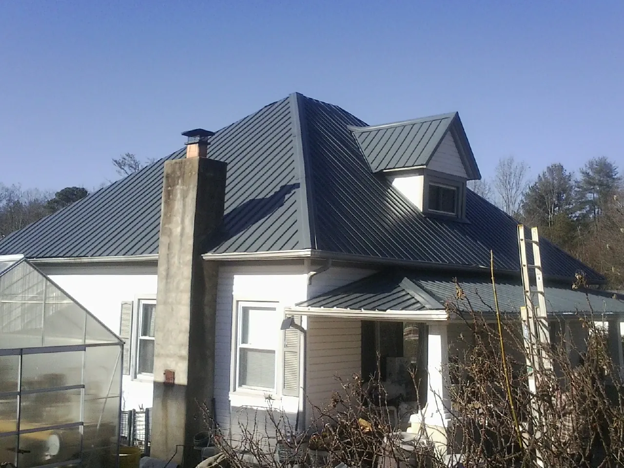 Dark blue standing seam metal roof on a white farmhouse with dormer — Slate & Tile Roof Repair by Roofing Brothers in Warden