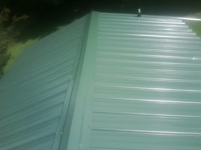 New green metal panels meeting at the ridge of a roof — Flat Roof Repair work by our crew in Warden