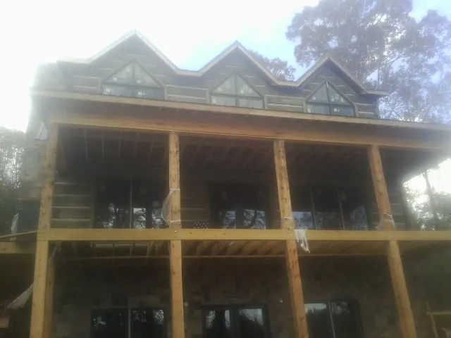 Dormers and porch framing on a large log home under construction — Roof Coating work by our crew in Warden
