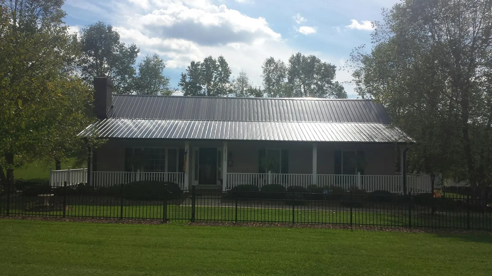 Gray metal roof on a brick ranch with a full width front porch — Gutter Guard Installation work by our crew in Warden